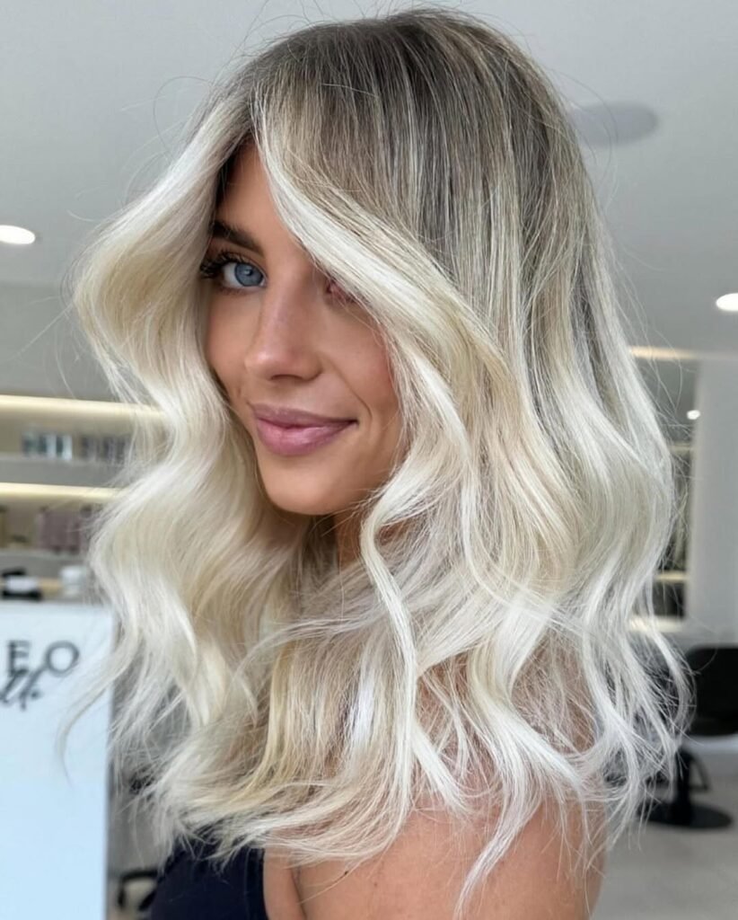 Bright blonde waves with dark roots showcasing trendy fall hair colors.