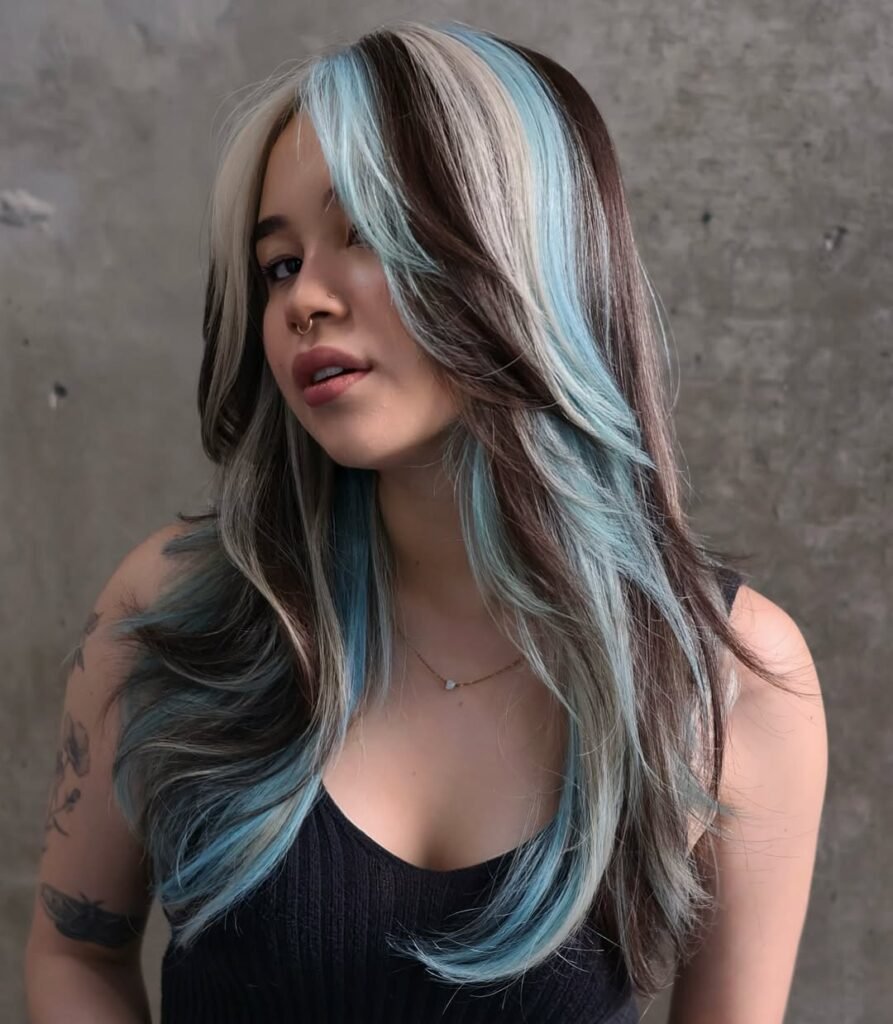 Woman with long brunette hair accented by icy blue and platinum streaks — a creative and cool interpretation of Fall Hair Colors.