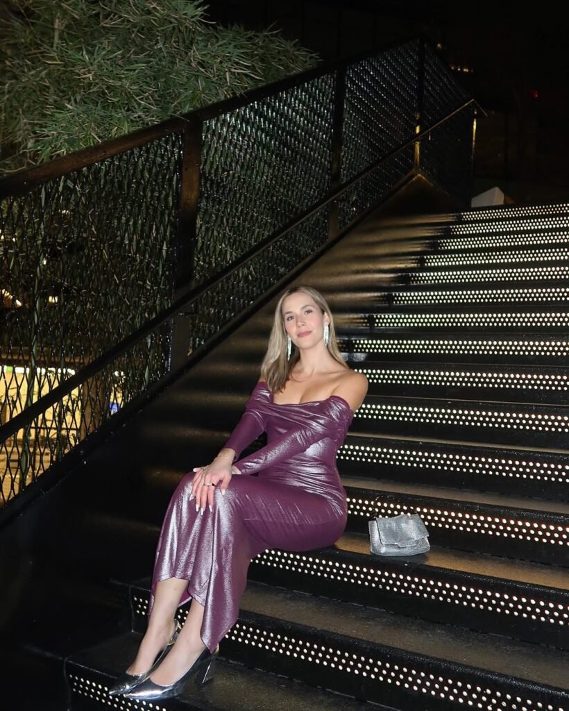 Woman sitting on illuminated stairs in a shimmering purple off-the-shoulder gown with silver heels — a dazzling Night Out Outfit.