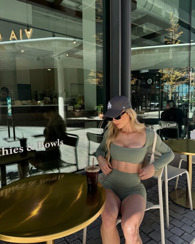 Gym outfit inspo featuring a sage green long-sleeve crop top and matching high-waisted shorts with a cap and iced coffee.