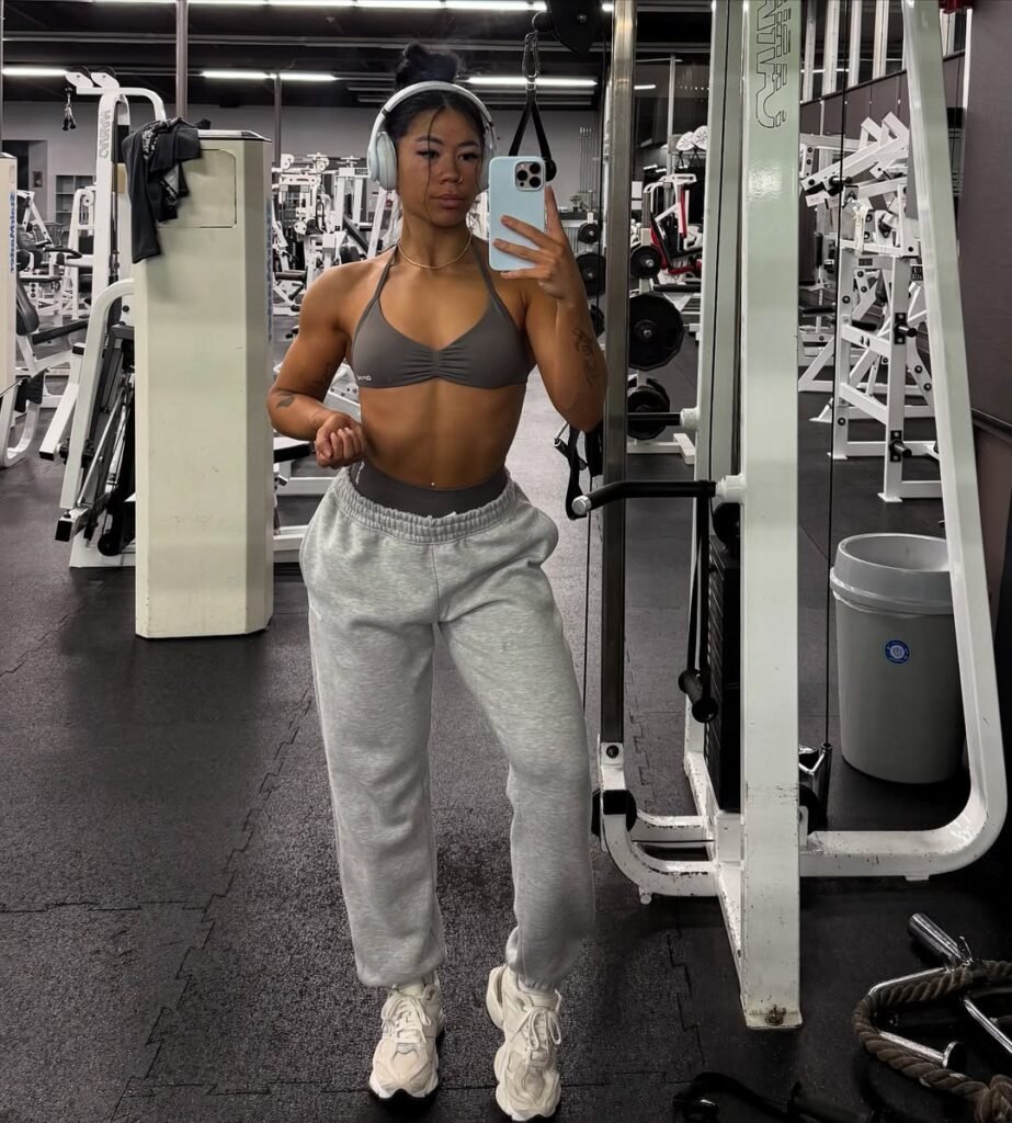 Laid-back gym outfit inspo with grey sweatpants and a brown sports bra, styled with headphones for a focused gym session.