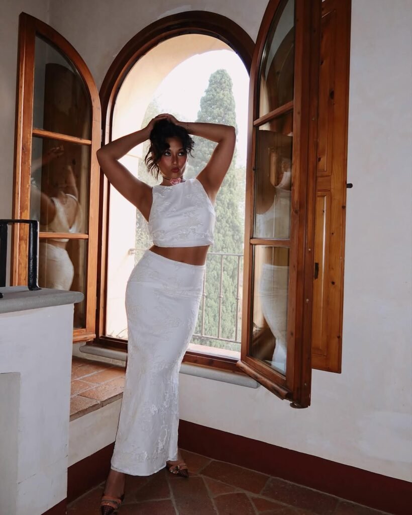 Woman posing in front of arched windows in a white matching set – perfect outfit inspo for elegant summer looks.