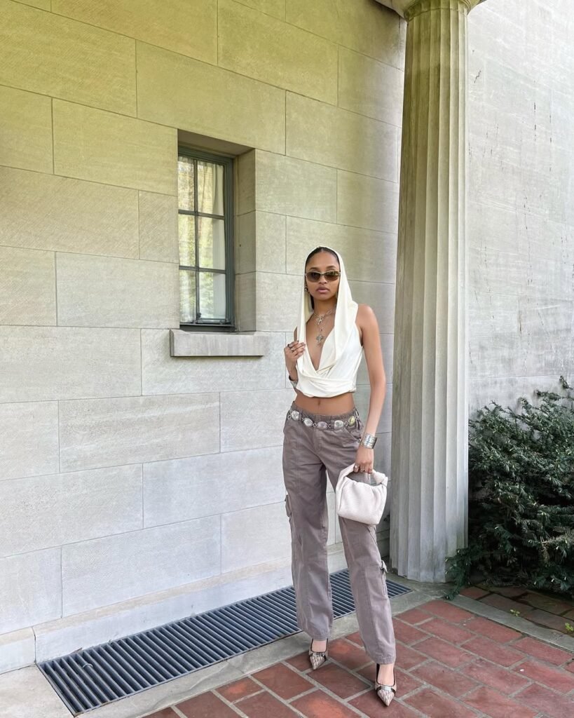 Urban outfit inspo with a hooded halter top and cargo pants, accessorized with bold jewelry.