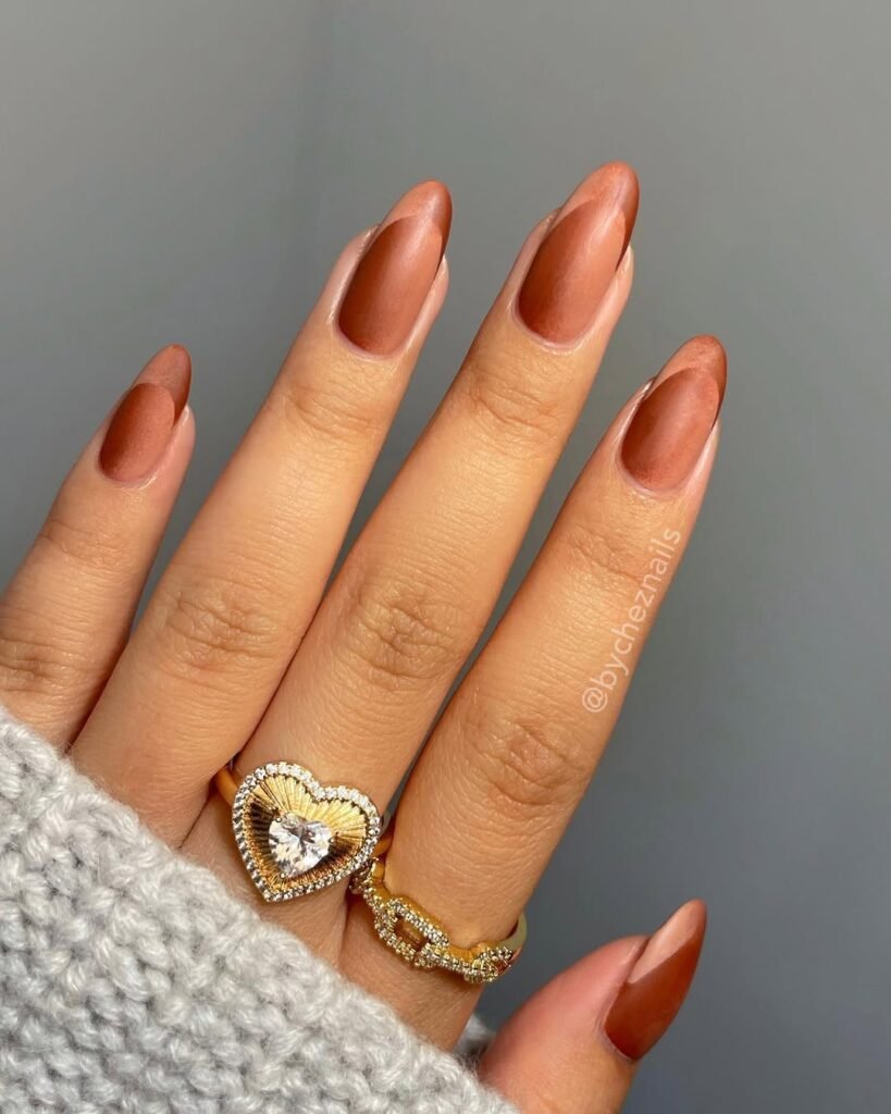 Elegant brown chrome almond-shaped nails paired with gold rings — perfect finishing touch for a chic Night Out Outfit.