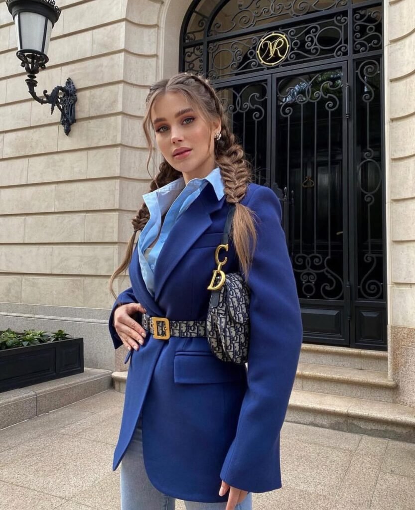 Woman wearing a royal blue belted blazer over a light blue shirt, paired with jeans and a Dior bag – elegant outfit inspiration for a polished city look.