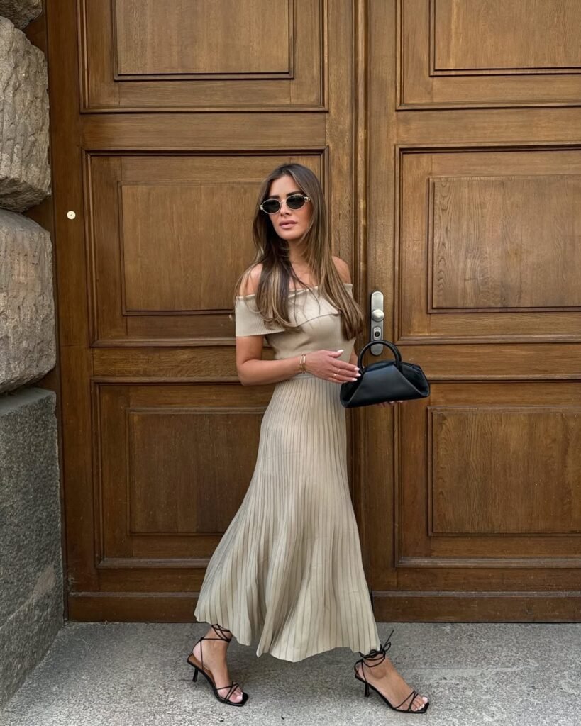 Woman in a beige off-the-shoulder pleated dress with strappy heels – an elegant outfit ideal for daytime outings.