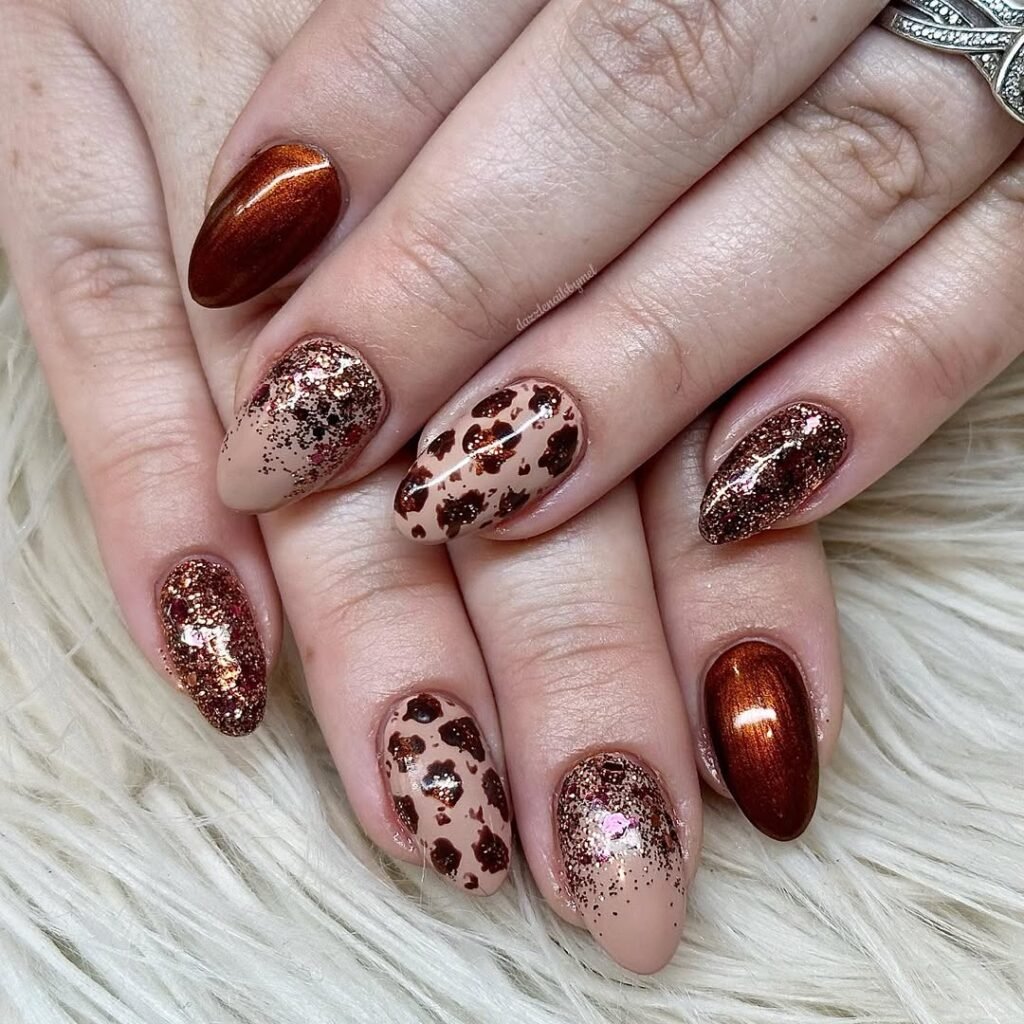 Sparkly copper and cheetah-print Fall Nail Colors on almond-shaped nude nails.