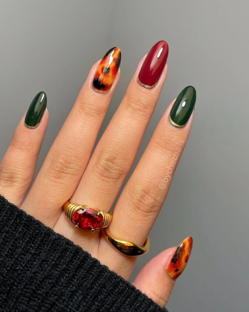 Bold autumn-inspired nail design with deep red, green, and tortoiseshell art — statement nails for your Night Out Outfit.


