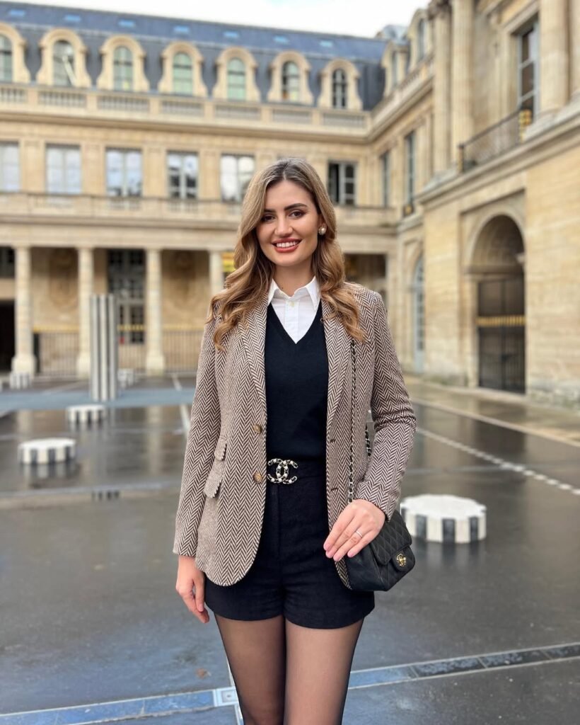 Business chic with a checked blazer, white shirt, black shorts, and tights – elegant outfit for professional settings.