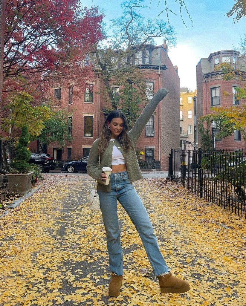 Trendy cardigan outfit with a cropped green cardigan, white crop top, and high-waisted jeans in a fall setting.