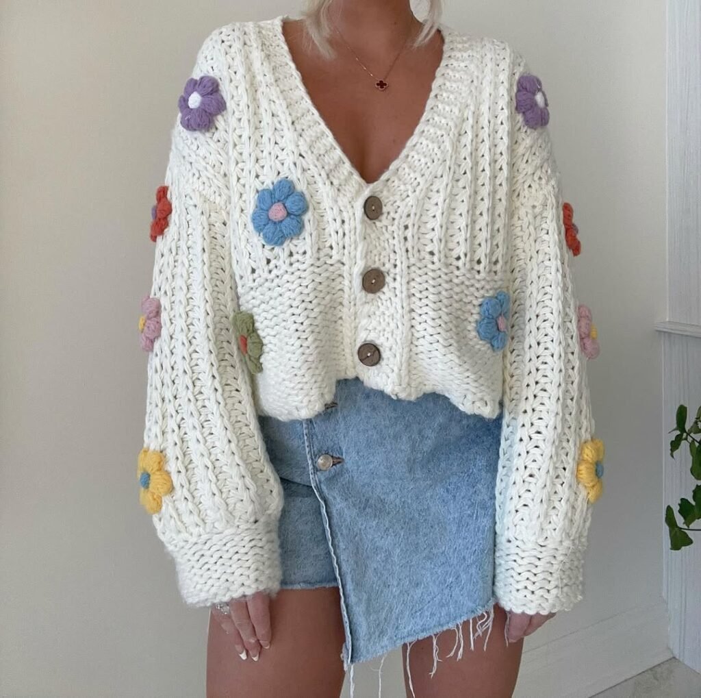 Playful white knitted cardigan outfit with floral patterns and a light denim mini skirt.

