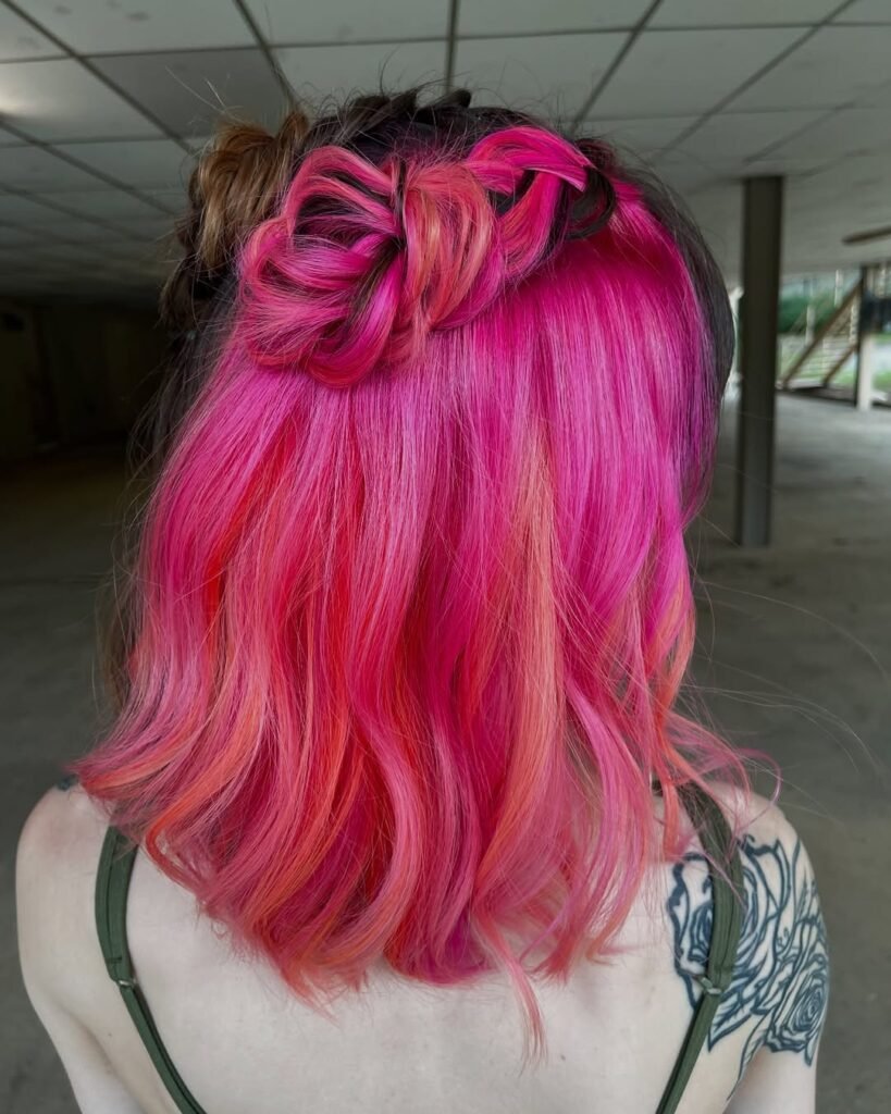 Bright pink wavy bob with twisted double buns – cute hairstyles for short hair.