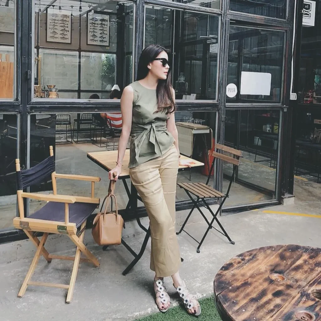 Stylish work attire featuring an olive green sleeveless peplum top paired with beige cropped trousers and white embellished sandals for a smart-casual office look.