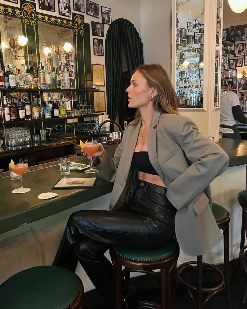 Classy outfit featuring a black bandeau top, oversized taupe blazer, and high-waisted leather pants, perfect for a stylish evening at the bar.