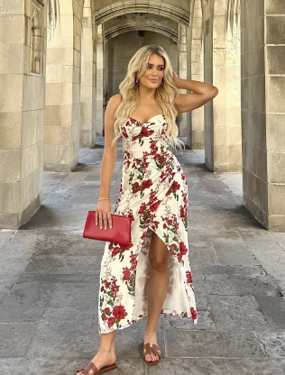 A woman wearing a floral white and red strapless high-low dress with a red clutch and sandals; romantic and classy summer outfit idea.