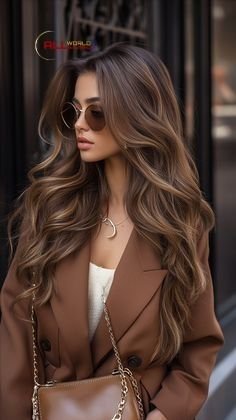 A woman with light brown hair styled in bouncy waves, showcasing a fresh, bright brown hair color idea with soft, dimensional highlights.