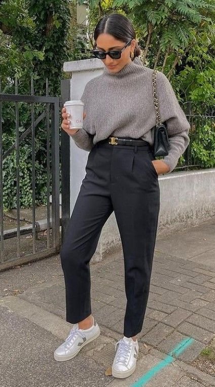 Stylish work attire consisting of a grey knit turtleneck tucked into black high-waisted trousers, paired with white sneakers, a black quilted bag, and sleek sunglasses for a cozy yet professional fall look.

