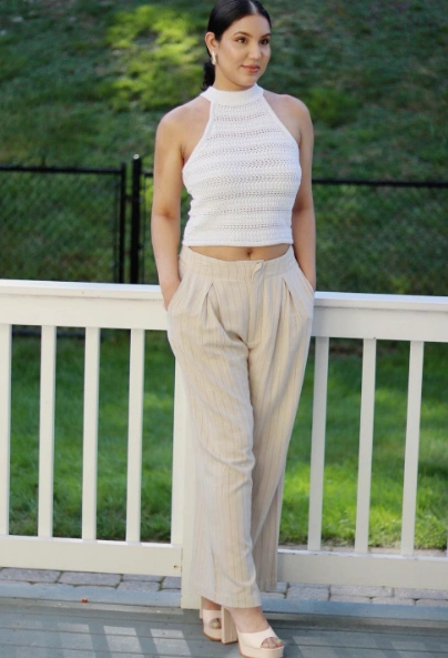 Neutral outfit with striped high-waisted trousers and a white crochet halter top, completed with nude heels — a refined choice for outfit ideas summer.