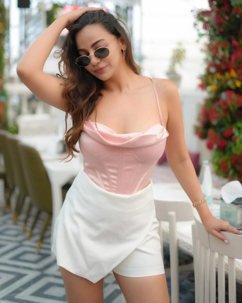 A woman wearing a pink satin top with a sweetheart neckline and white high-waisted shorts, accessorized with sunglasses, in a chic brunch outfit for summer.