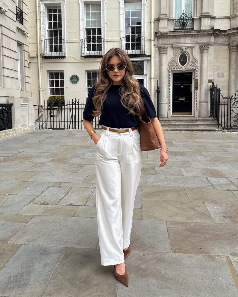 Chic street-style look featuring a stylish work outfit with a navy top and white trousers.