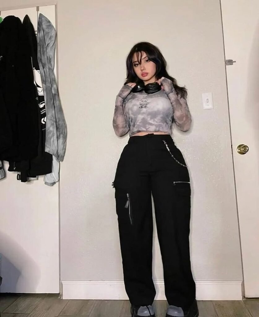 Grunge Outfits: Person with long dark hair wearing a gray tie-dye mesh long sleeve crop top and black pants posing indoors.