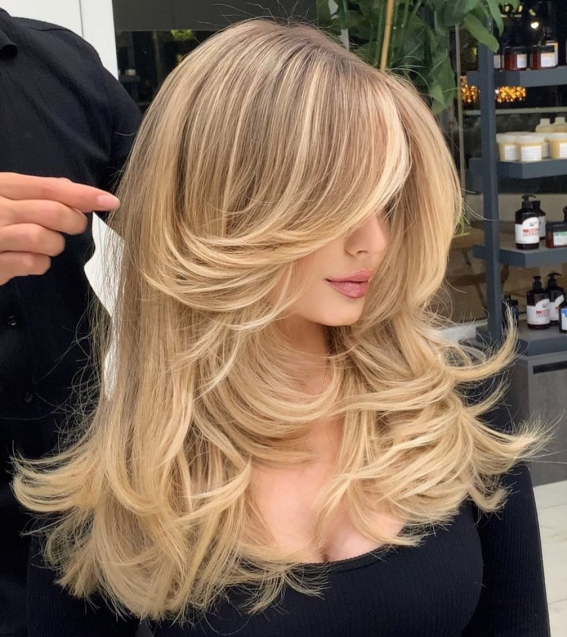 A woman with sleek, straight brown hair, showcasing a chic, sun-drenched brown hair color idea with soft layers.