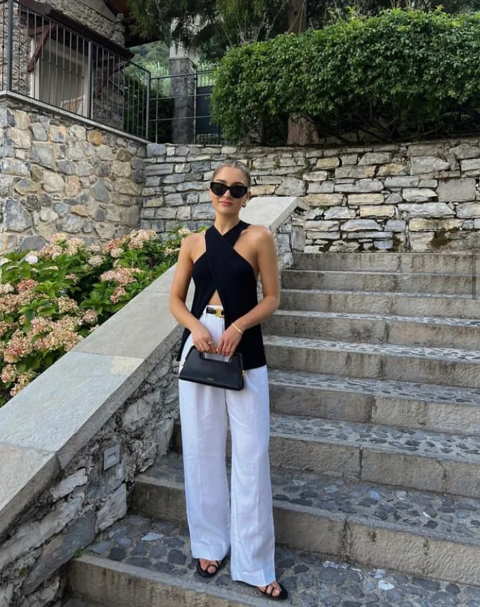 Elegant linen pant outfit featuring white pants and a sleeveless black top, accessorized with black sunglasses and a small handbag.