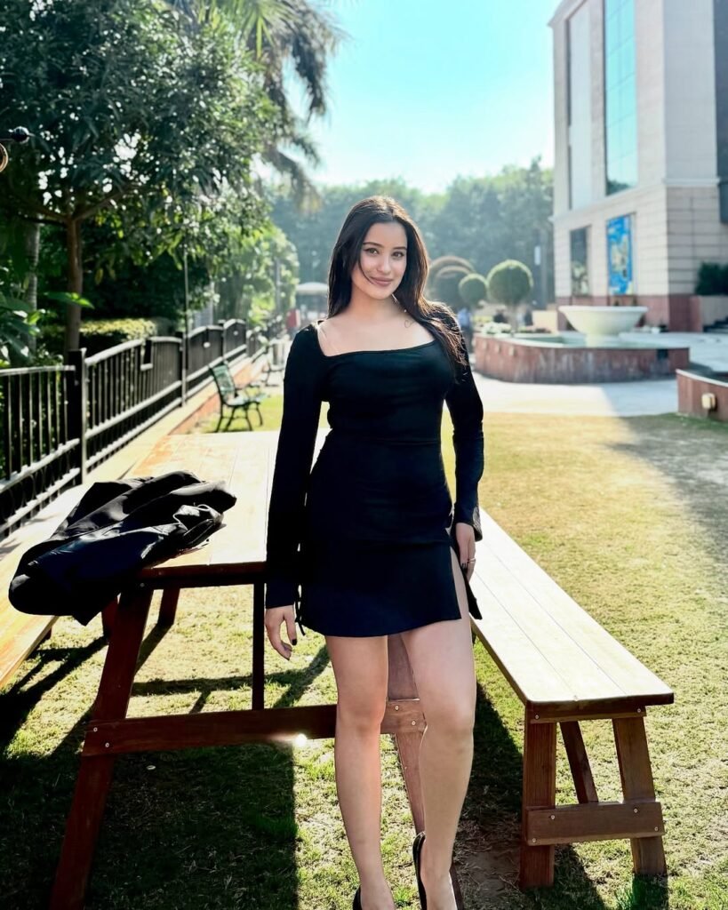 A woman in a black summer brunch outfit featuring a fitted long-sleeve top and mini skirt, posing confidently outdoors near a park bench.