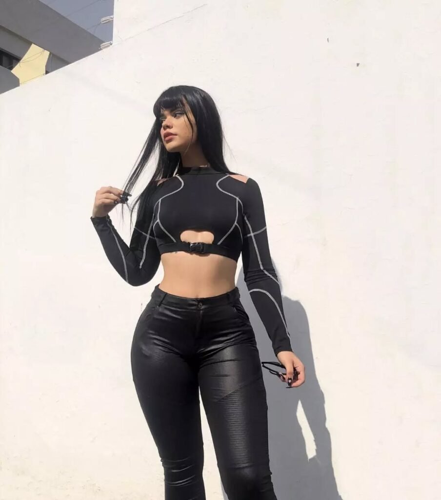 Grunge Outfits: Person wearing a black crop top over fishnet top and olive cargo pants crouching indoors, paired with black platform boots.