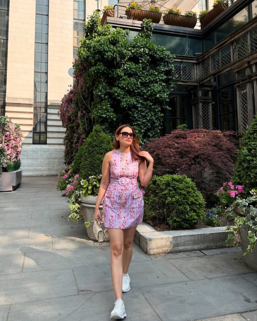 Woman walking indoors wearing a sleeveless, floral-patterned dress with a belt, showcasing a chic and comfortable outfits verano.