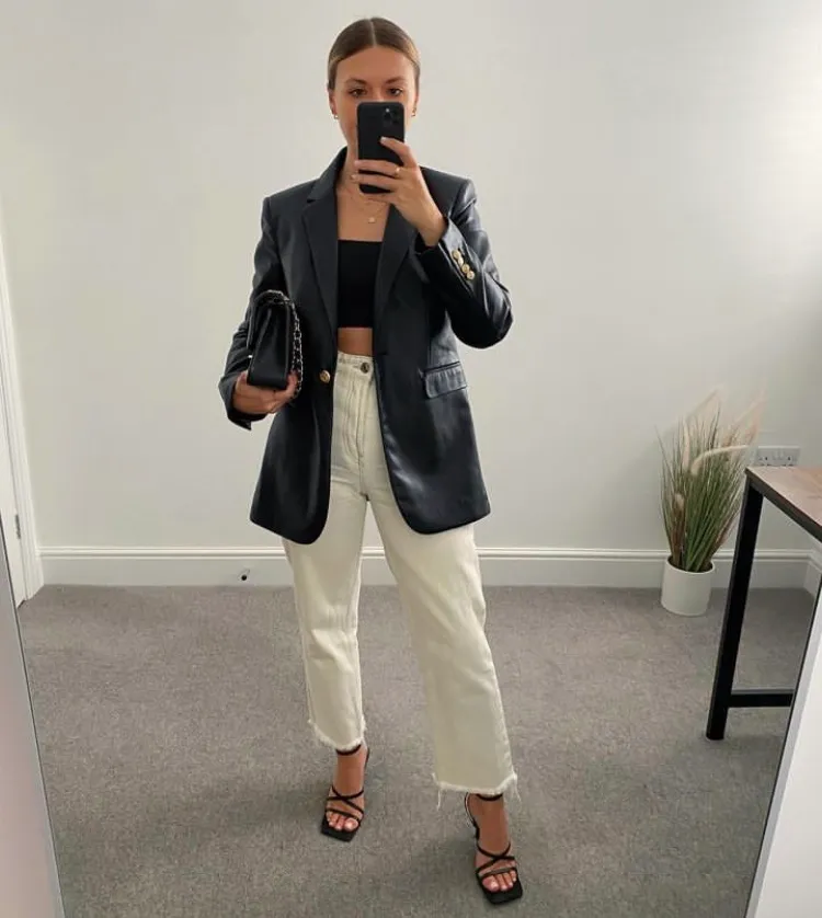 Casual yet edgy Leather Blazer outfit featuring a black crop top, cream straight jeans, strappy heels, and a chain-strap handbag.