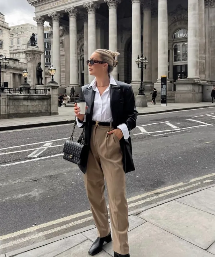 Classy Leather Blazer street style paired with a white button-up shirt, beige trousers, and black boots for a polished city look.
