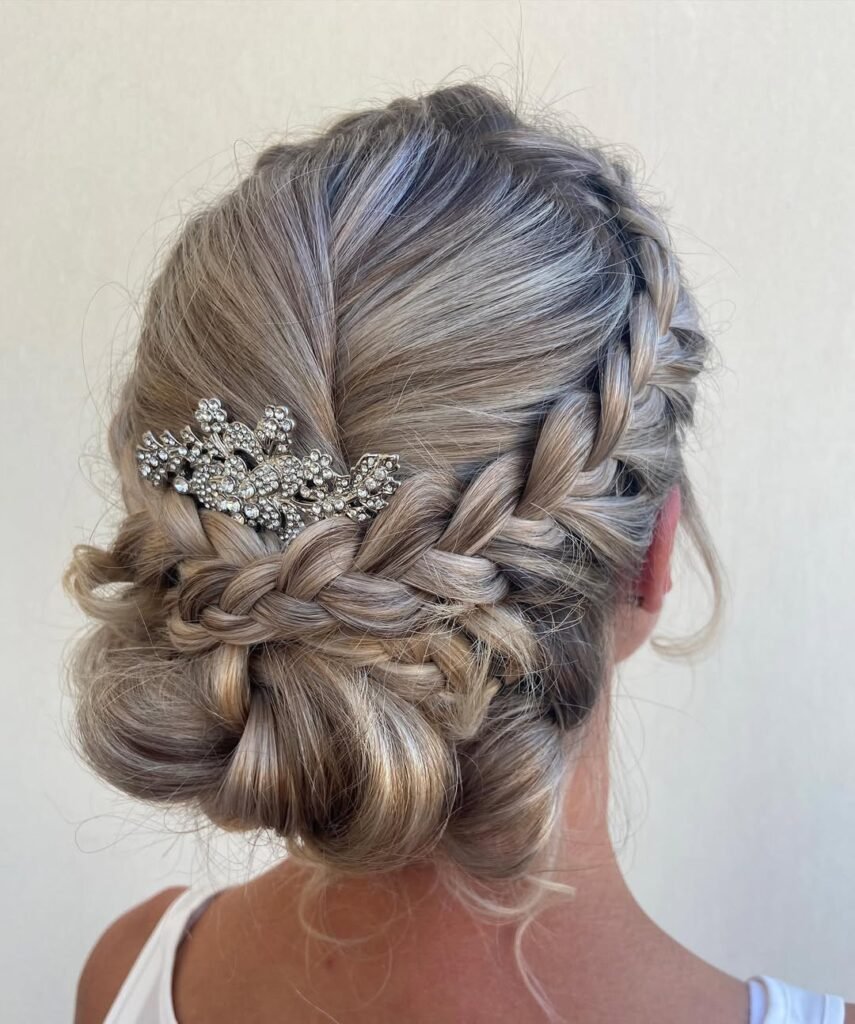 Elegant hairstyle styled in a braided low bun accented with a sparkly crystal hairpiece.