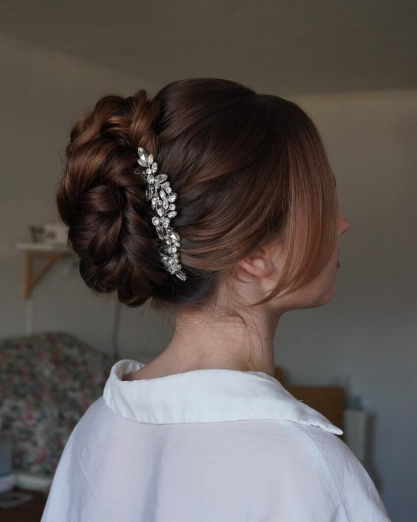Elegant braided updo with rhinestone hairpin for formal events.