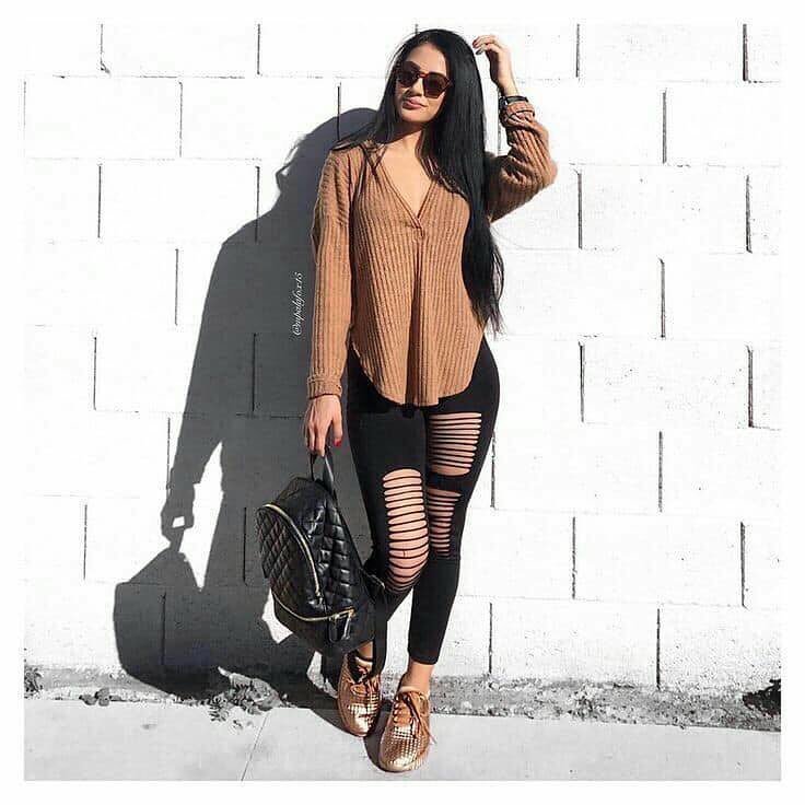 Woman in ripped leggings and brown sweater posing outdoors – Outfits Casuales perfect for a trendy fall look.