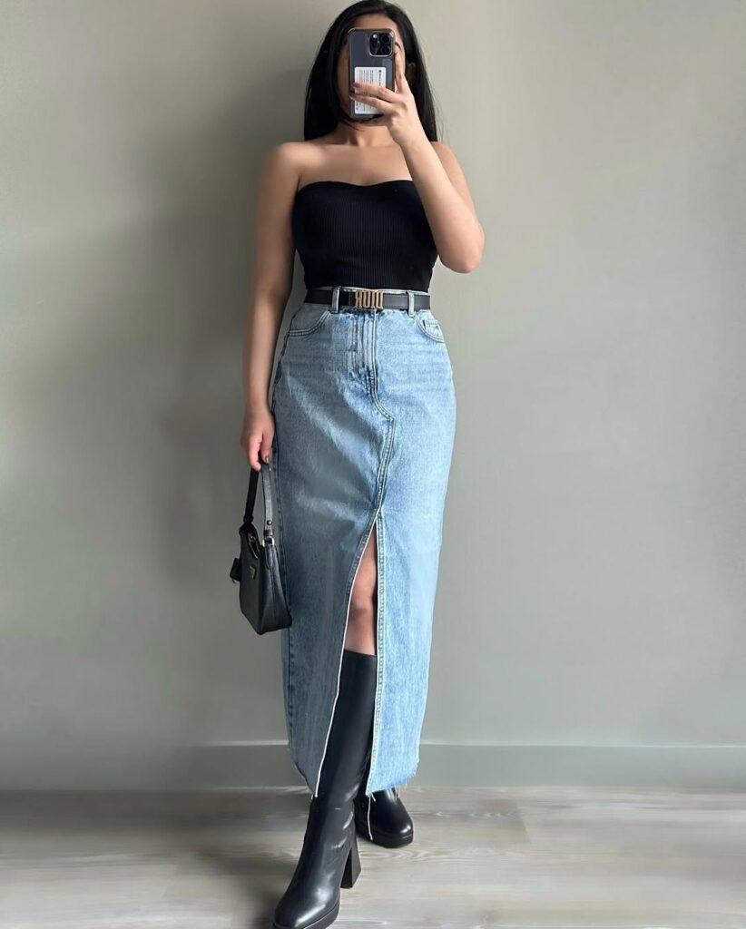  A woman in a black strapless top and light blue front-slit denim skirt, styled with tall black boots and a small handbag — Bold Skirt Outfits with modern edge.
