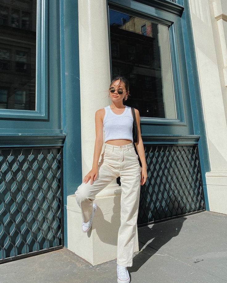 Trendy street look with white crop top and high-waisted cream jeans paired with sneakers. Outfits Casuales.