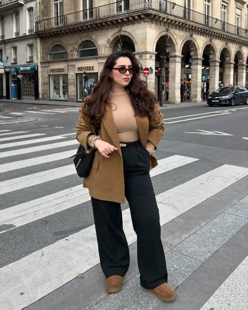 Woman walking on street wearing a brown blazer with black pants and tan shoes, showcasing stylish blazer outfits.