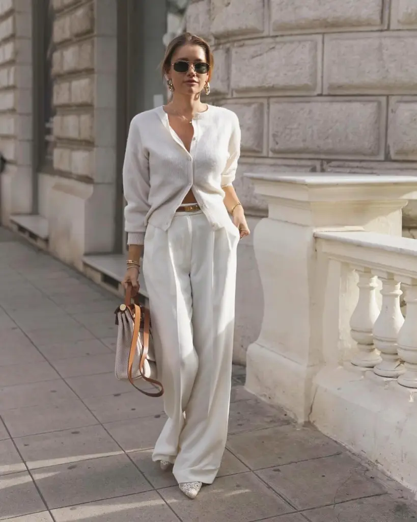 Woman wearing elegant white cardigan and pants styled in old money outfits.
