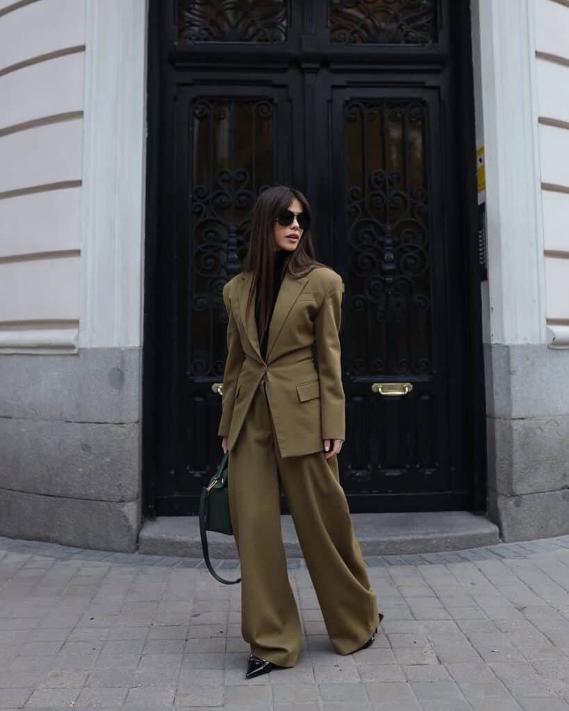 Woman standing in front of a black door wearing a matching brown blazer and pants, perfect blazer outfit inspiration.
