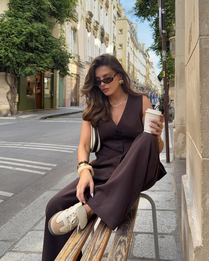 Woman in brown jumpsuit with sneakers, sitting in Paris street – old money outfits blending comfort and elegance.
