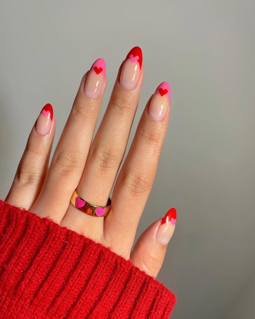 Valentine-inspired nail ideas featuring red and pink heart tips on almond-shaped nails.