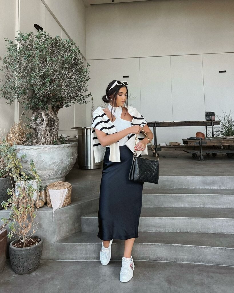 Casual coffee date outfit with a black slip dress, striped cardigan, and white sneakers.