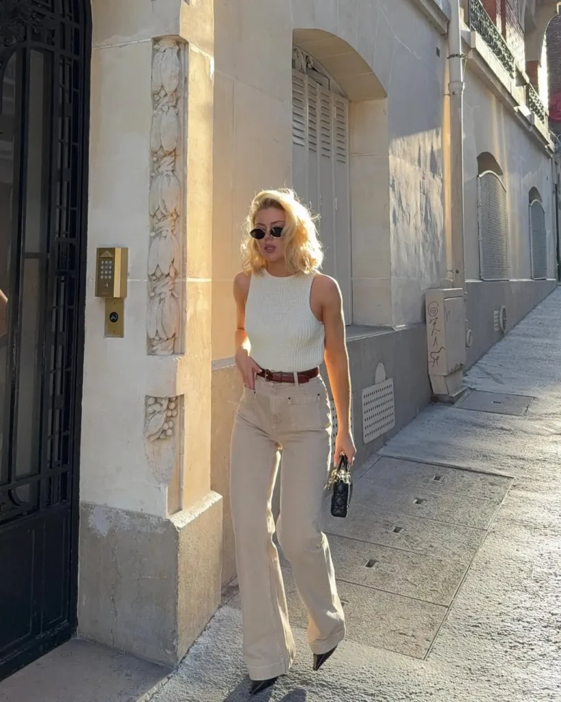 Casual Summer Outfits with a sleeveless ivory knit top tucked into beige wide-leg trousers, accessorized with pointed black heels, a leather belt, and black mini bag—perfect for strolling sunlit city streets.