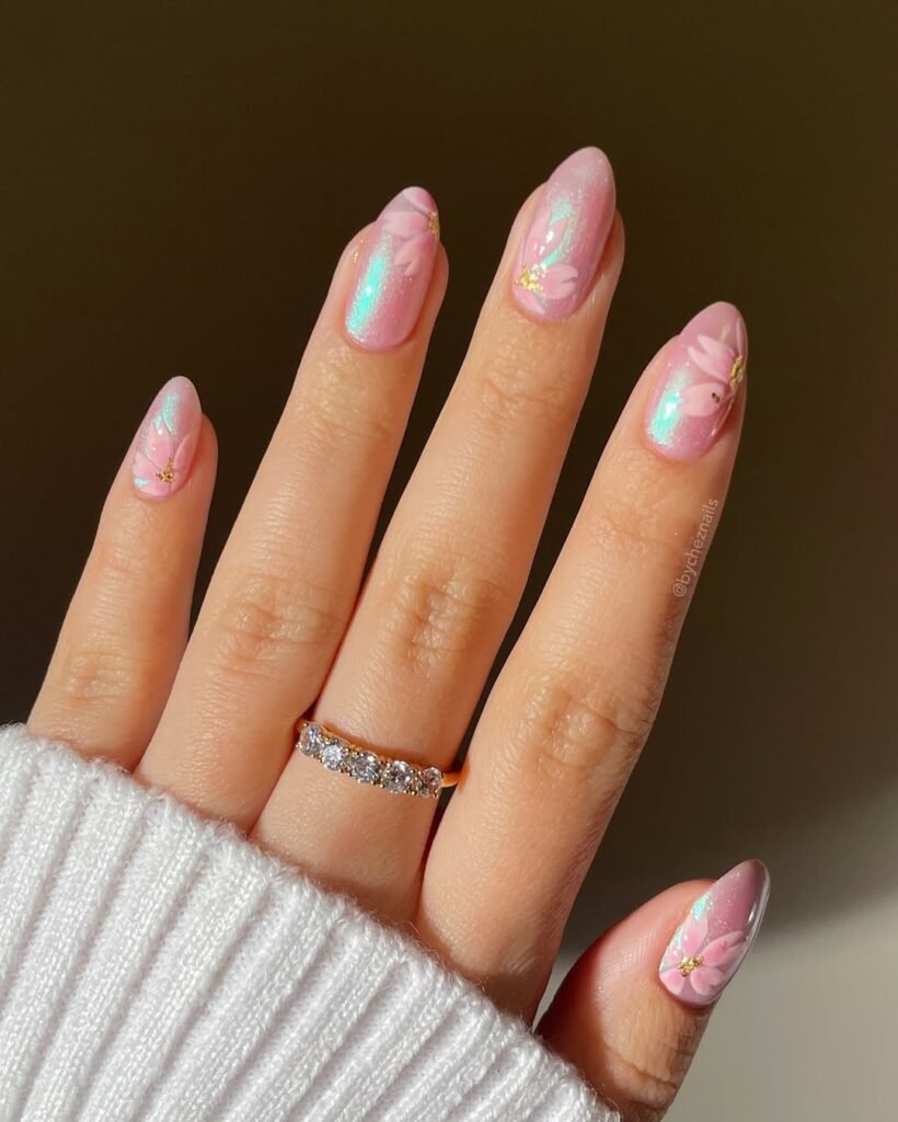 Spring Nail Ideas with pink iridescent polish and hand-painted light pink flower petals, adding a touch of shimmer and gold accents.