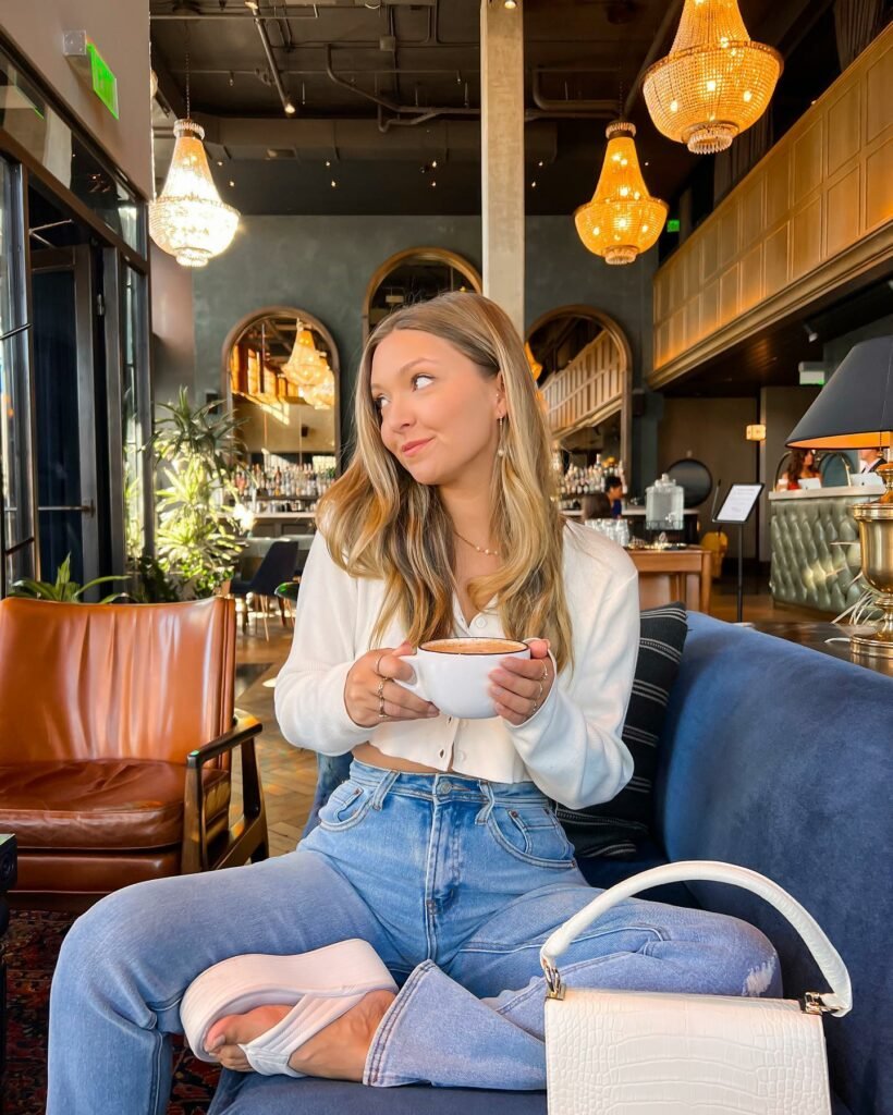 Cozy coffee date outfit with a white blouse, light blue jeans, and white shoes, paired with a small white handbag.