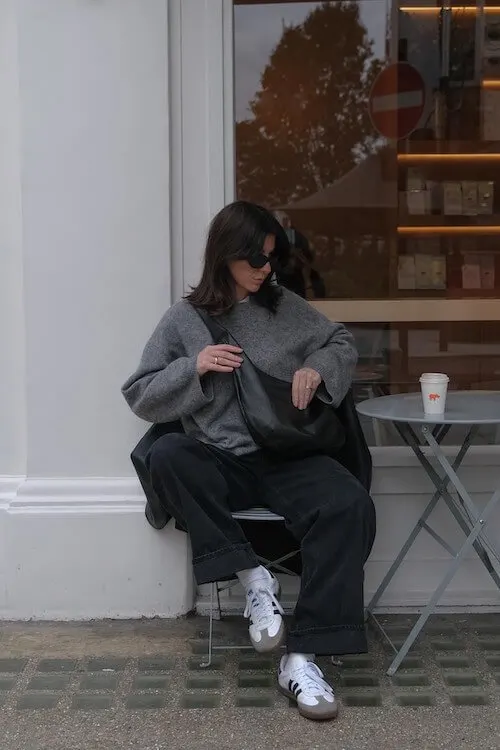 Urban street outfit styled with Adidas Samba Outfits, pairing a grey oversized sweater with wide-leg black jeans.