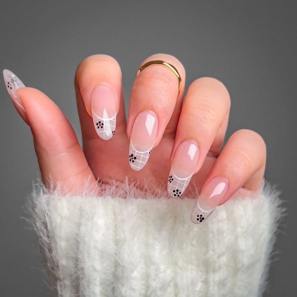 Creative nail ideas featuring white grid French tips and black floral accents on clear nude nails.