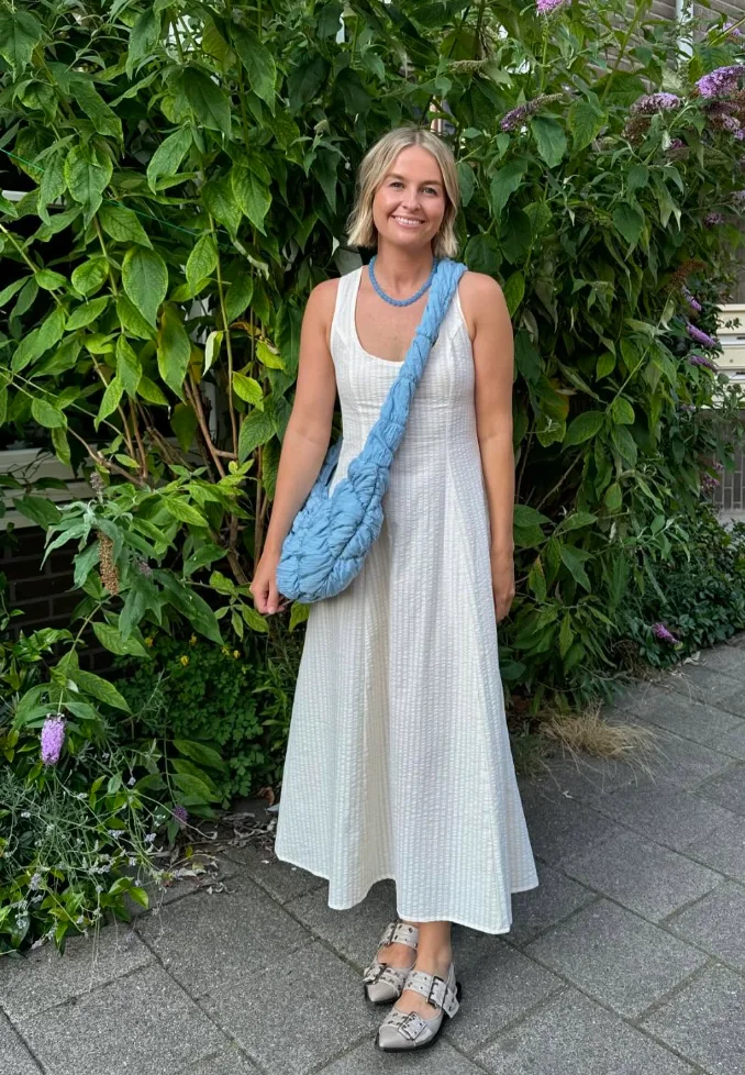  Woman in a white sleeveless maxi dress and statement accessories, delivering a light and elegant modest summer outfit.