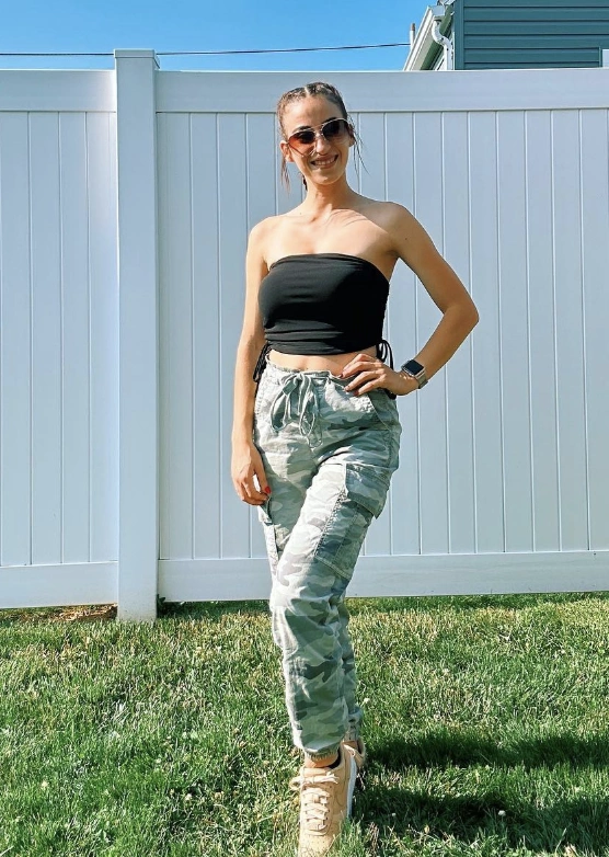 Light-toned Camouflage Pants Outfit paired with a strapless black crop top and beige sneakers, styled for a sunny outdoor look.